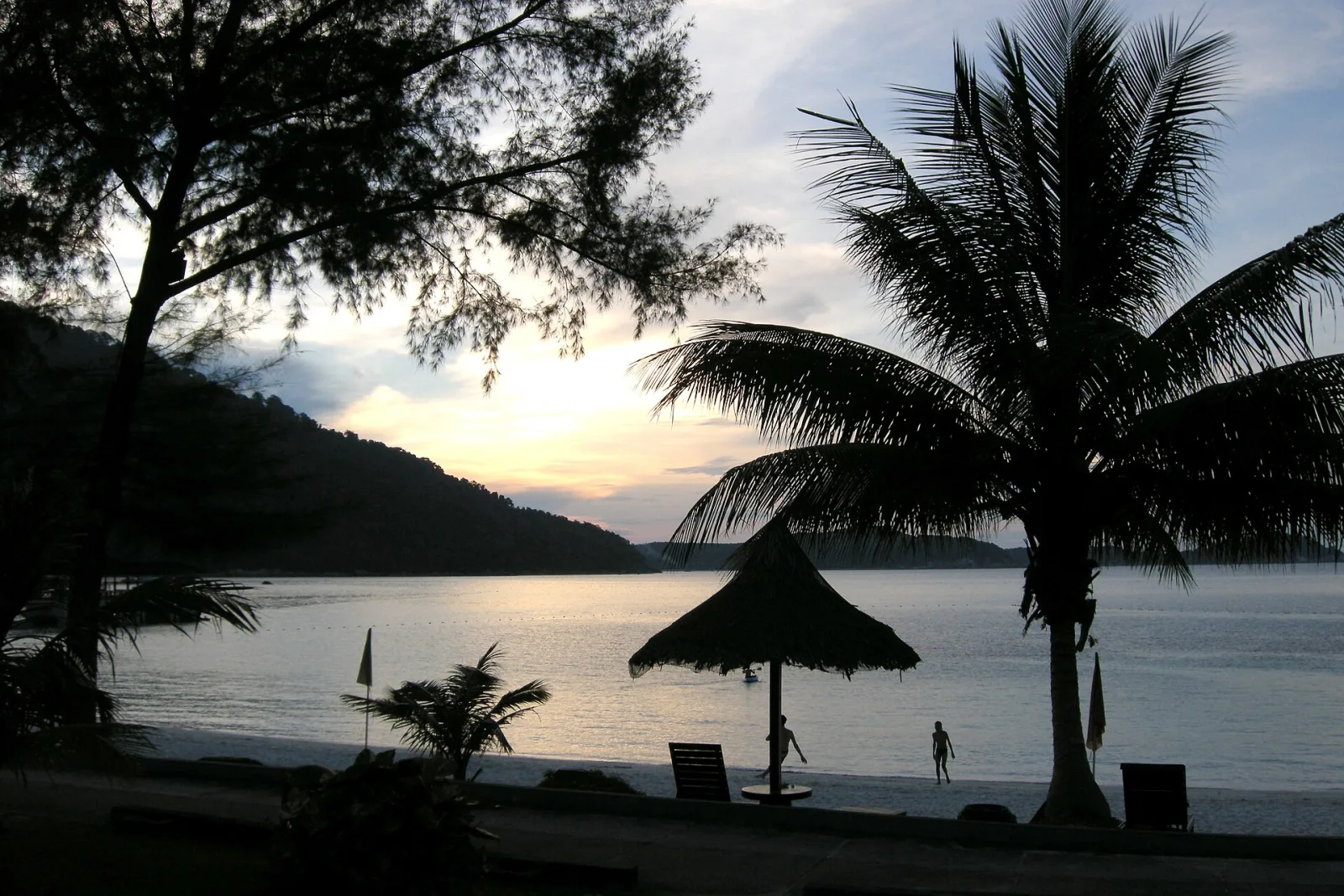 Silhouetted palms and calm sea at dusk on the Perhentian Islands.