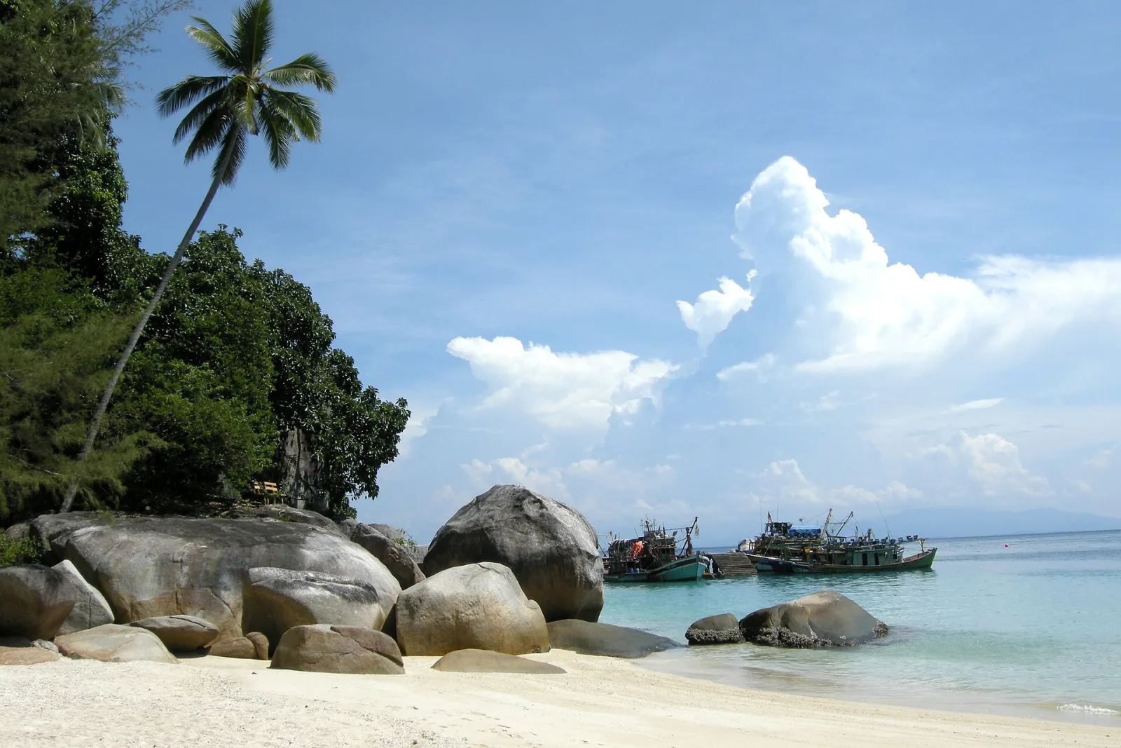 Granite boulders and a moored boat beside a white beach on Perhentian Besar.