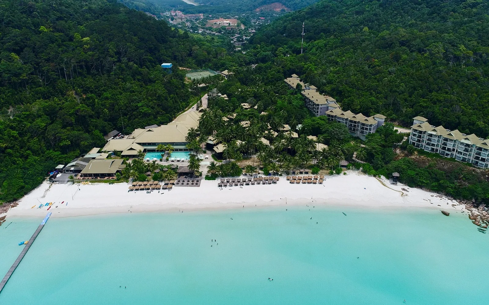 Aerial view of a forested Redang coast and bright white beach.